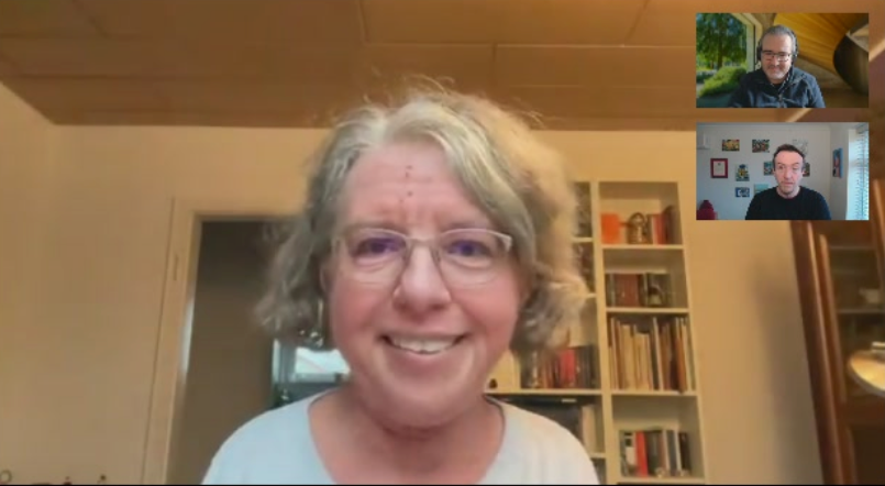 A screenshot from a podcast recording featuring Katrin Langensiepen as the main speaker. She is a middle-aged woman with short, curly gray hair, wearing glasses and a light-colored top, smiling at the camera. Behind her is a bookshelf filled with books and decorative items. In the top-right corner, two smaller video windows show the podcast hosts; one is wearing glasses and a dark jacket, with a blurred outdoor background, while the other is in a room with framed pictures on the wall, wearing a black shirt.